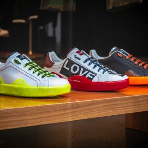 Vibrant colored sneakers displayed on a wooden table in a London store.