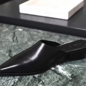 Stylish black leather shoe on a textured marble surface, showcasing modern elegance.